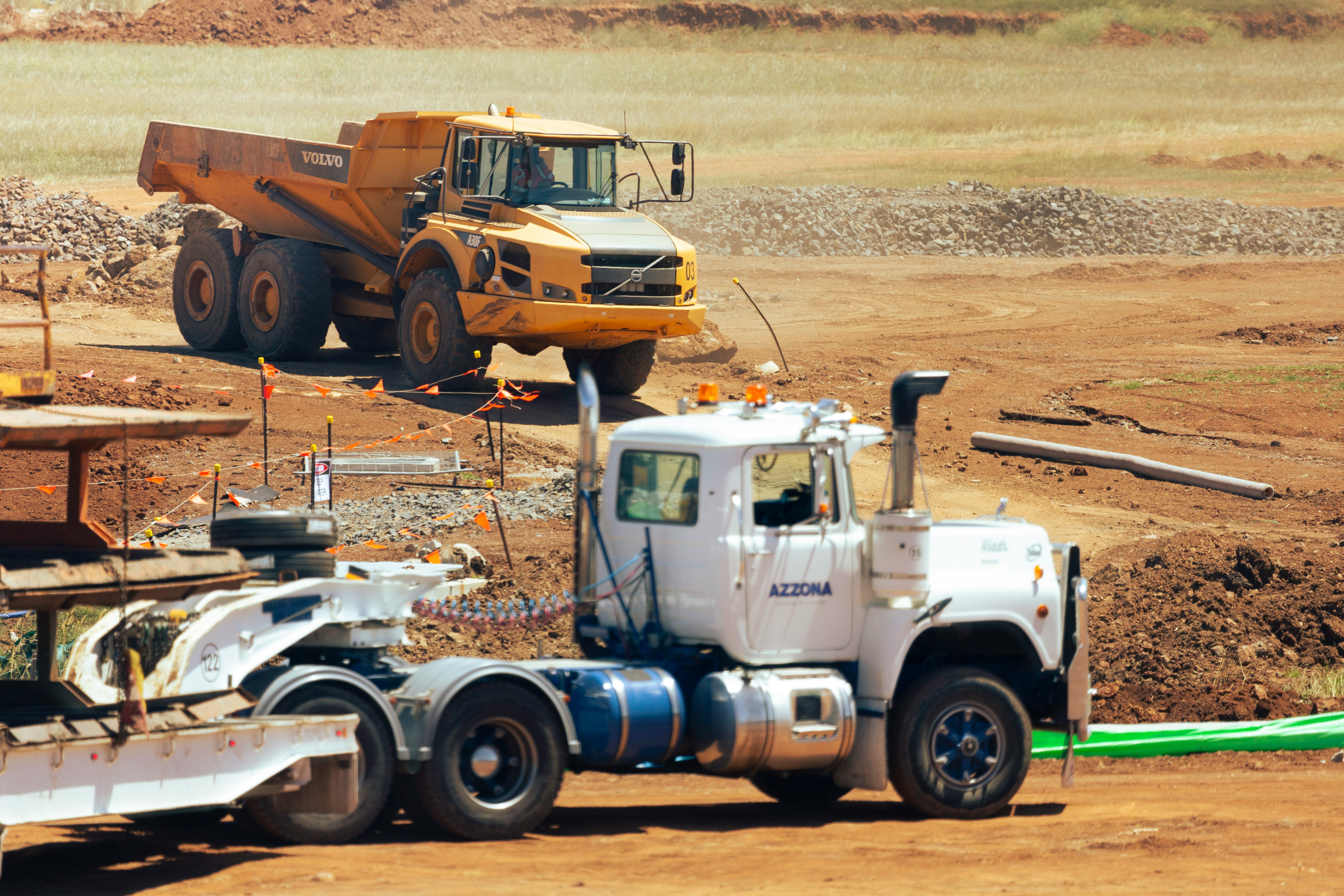 Heavy-duty truck with a lowboy trailer successfully transporting a Volvo A30F articulated dump truck, showcasing reliable heavy equipment hauling for construction and mining operations.