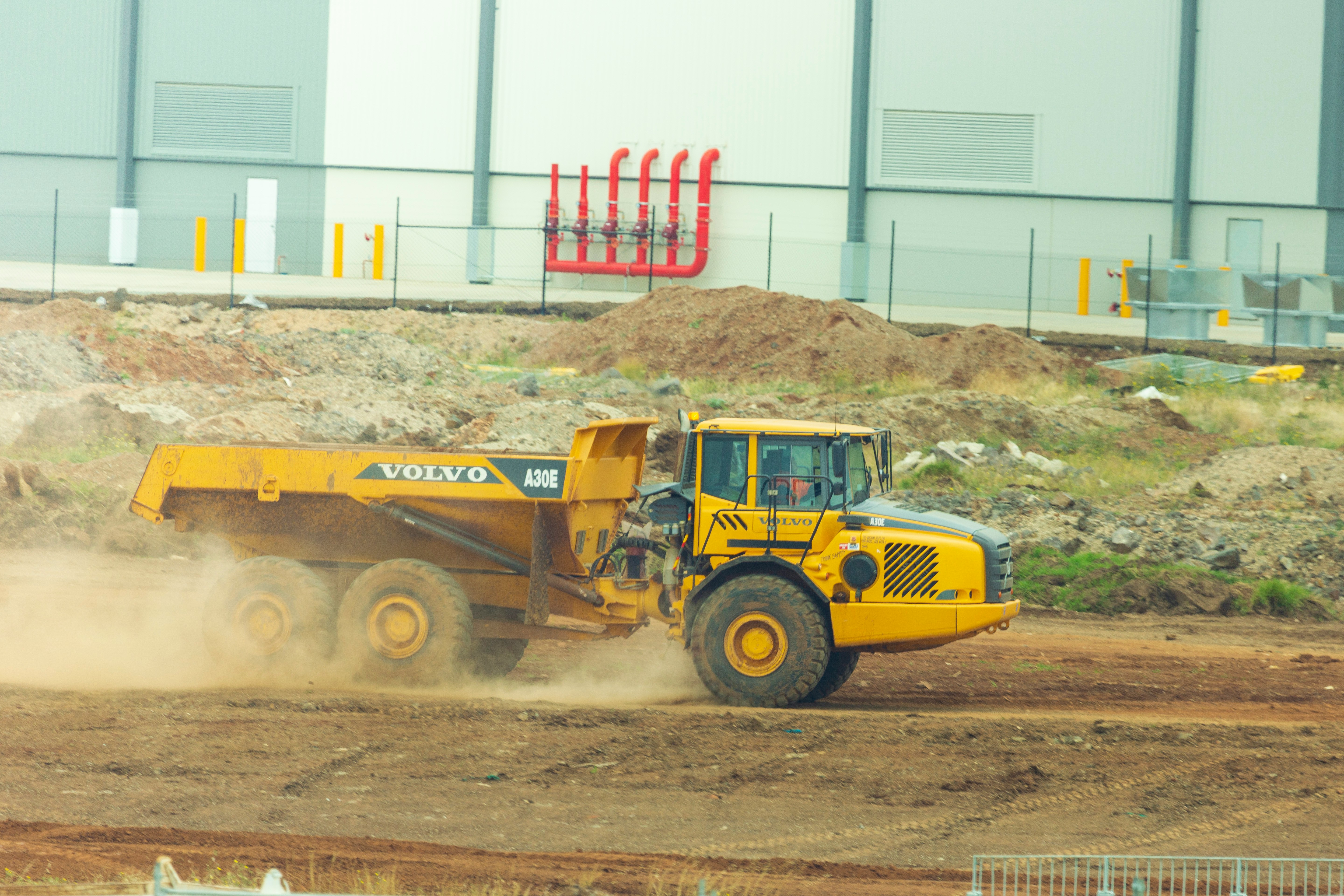 Volvo A30E articulated dump truck hauling dirt on an active job site, heavy-duty earthmoving hauler with dust trail.