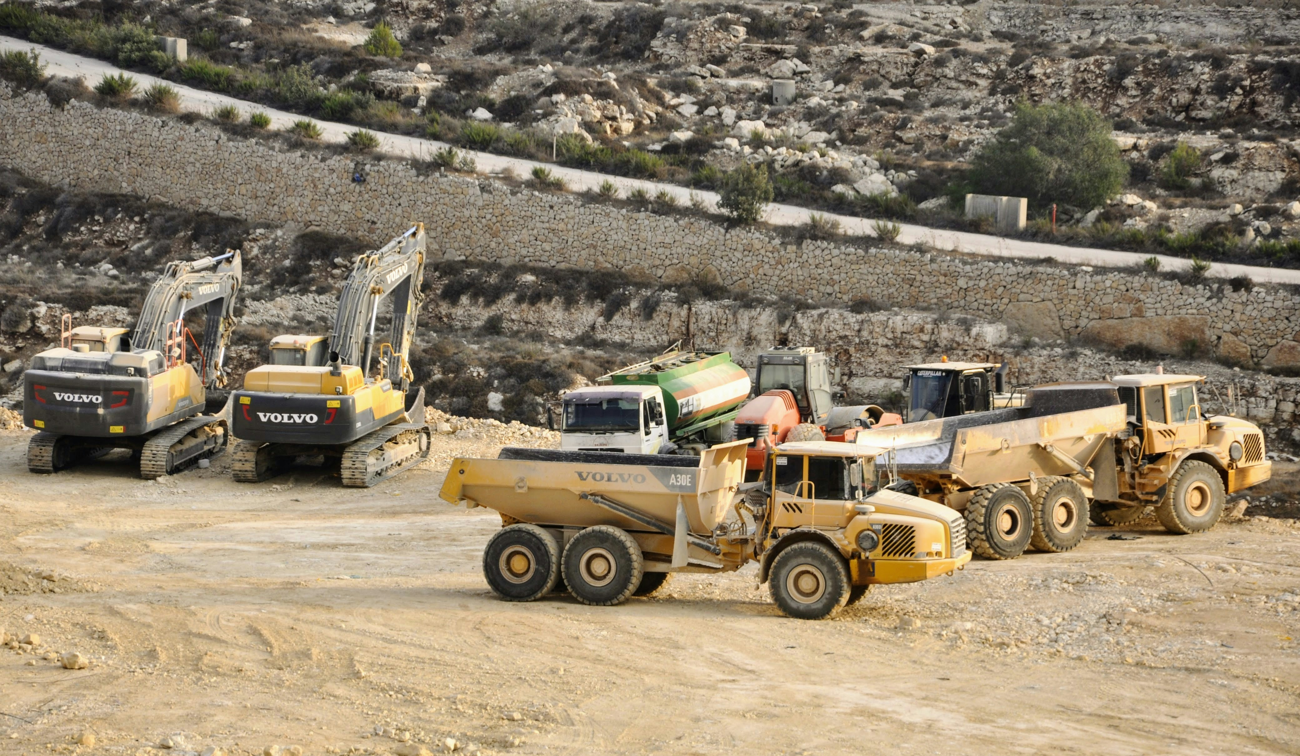 Quarry fleet with Volvo excavators and A30E articulated dump trucks parked on site, ready for mining and earthworks operations.