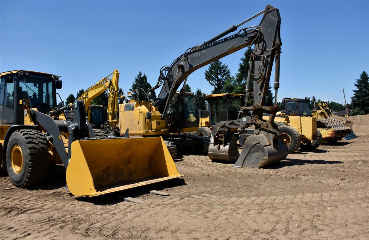 Row of heavy equipment lined up at an auction yard