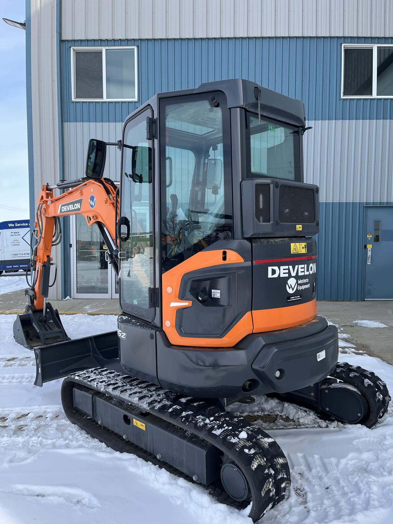 Zero tail swing mini excavator working close to a building wall