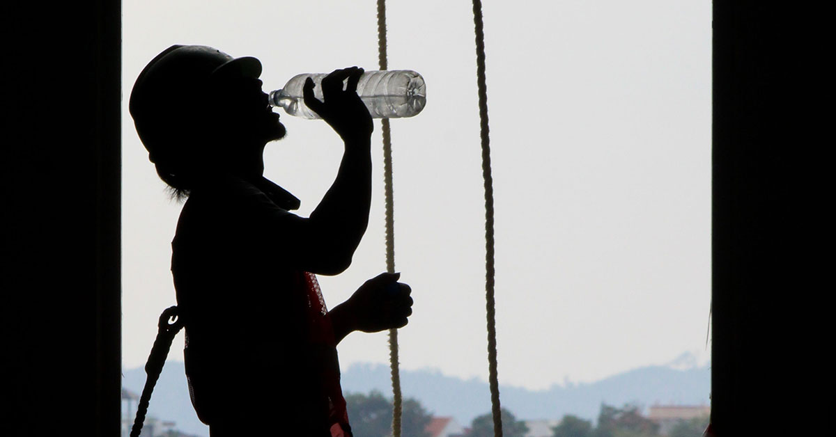 Silhouette of a construction worker hydrating on site with a plastic bottle. Image: Pexels/Iman Taufik